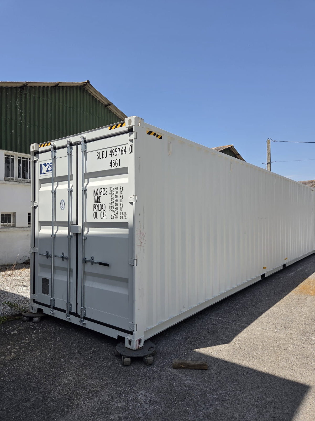 Container maritime 40 pieds High Cube premier voyage, blanc, posé devant l'atelier Contain Life à Trèbes, portes fermées à barres de verrouillage et marquages d'origine