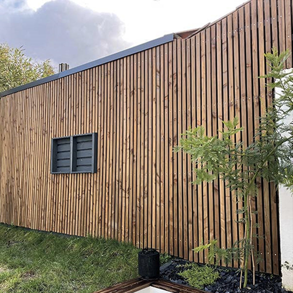Maison container à Villedubert habillée d'un bardage bois à claire-voie vertical, toiture terrasse à acrotère métallique sombre et volet persienné anthracite